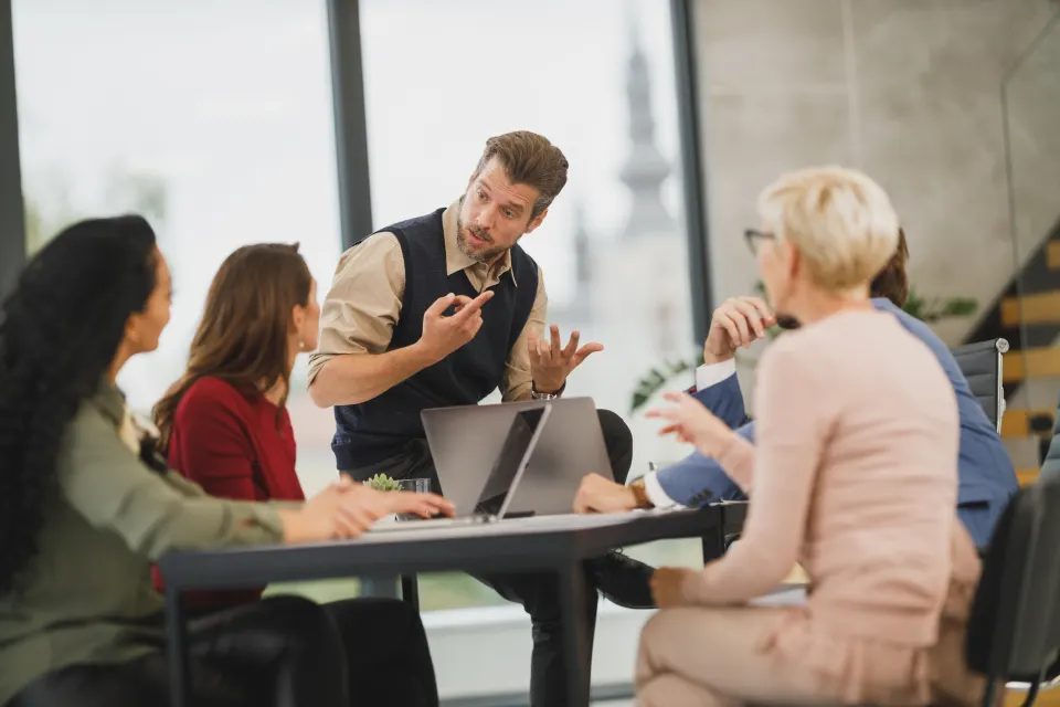 A team leader talking with four colleagues around a table